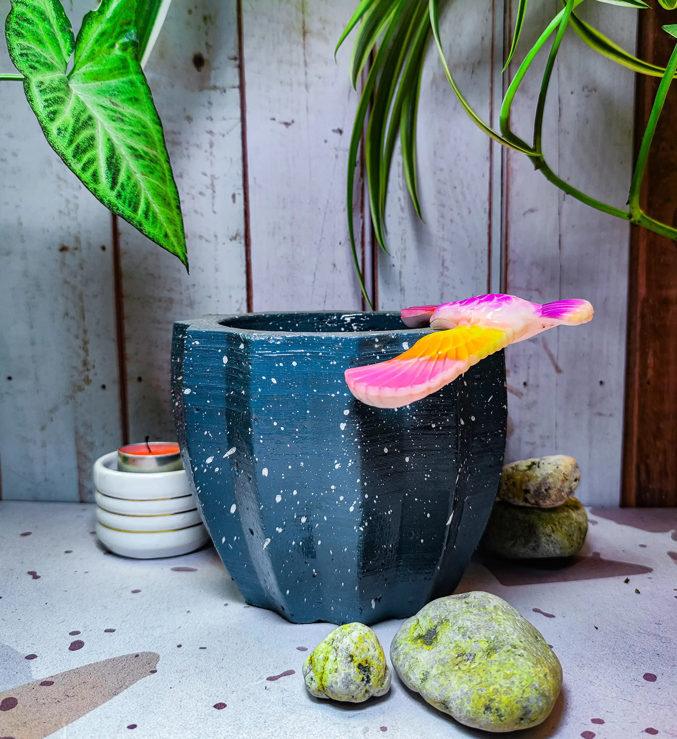 Maceta Zucca Azul Marino de concreto con forma de calabaza y 12 puntas, acabado jaspeado, en ambiente interior moderno con planta.