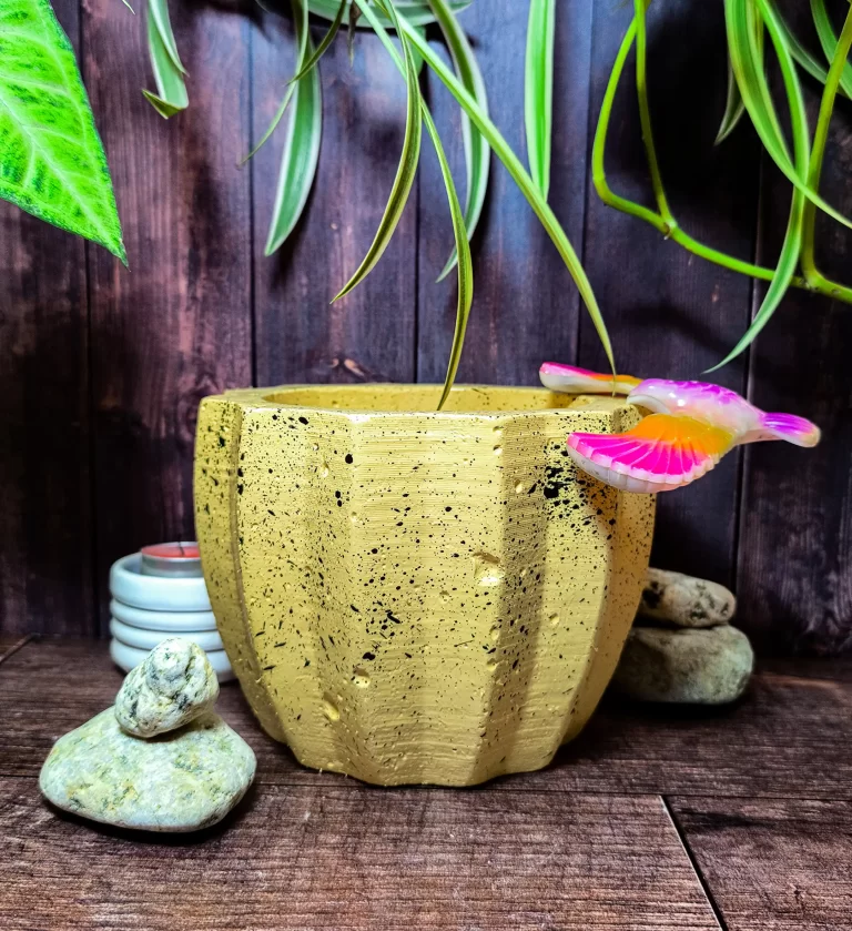 Maceta Zucca Amarilla de concreto con forma de calabaza y 12 puntas, acabado jaspeado, en ambiente interior moderno con planta.