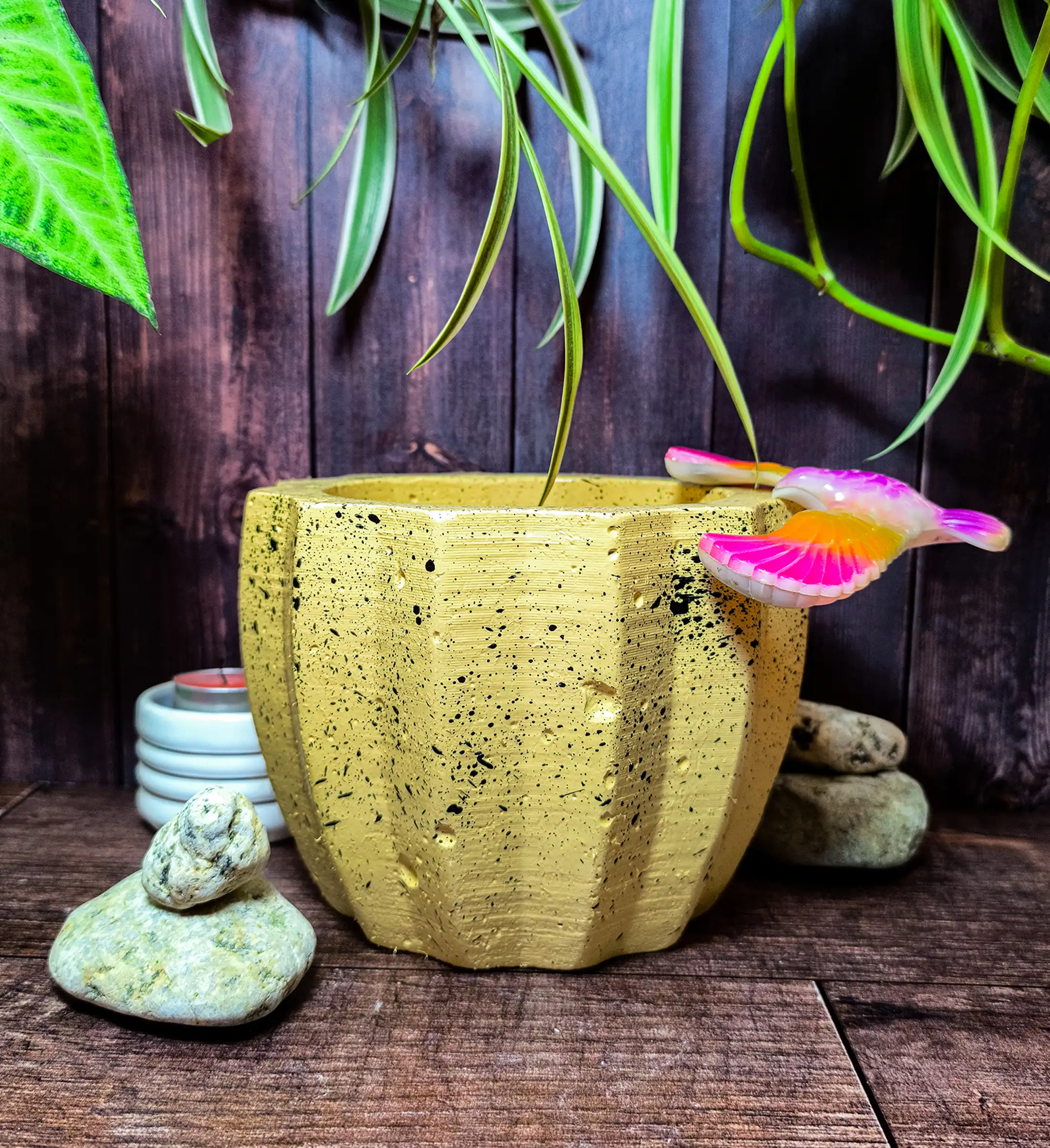 Maceta Zucca Amarilla de concreto con forma de calabaza y 12 puntas, acabado jaspeado, en ambiente interior moderno con planta.